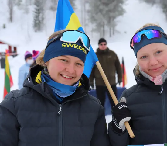 Två juniorer glada juniorer med svensk flagga under skidorienterings VM i Finland