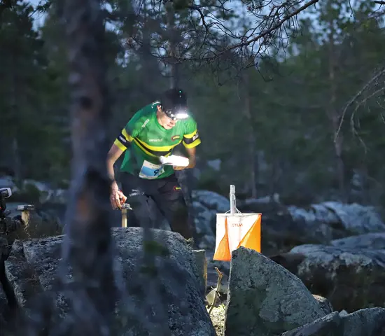 NTNUI-löpare stämplar vid en kontroll i mörkret på Tiomila i Skellefteå 2023.