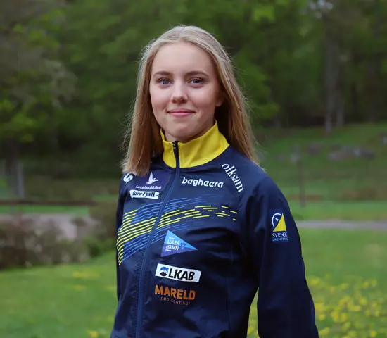 Hanna Lundberg med grön gräsmatta och skog bakom sig.