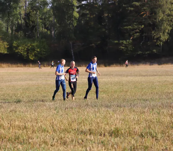 Tjejer värmer upp på en åker innan SM-stafett 2024